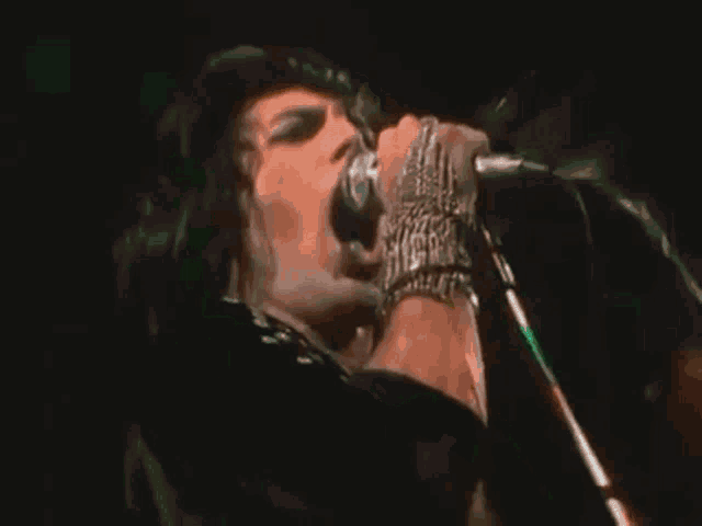 a man is singing into a microphone while wearing a bracelet .