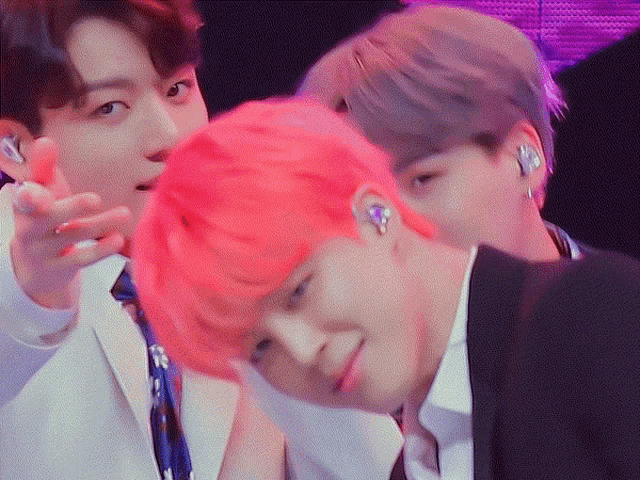 a group of young men with pink hair are standing next to each other in a room .