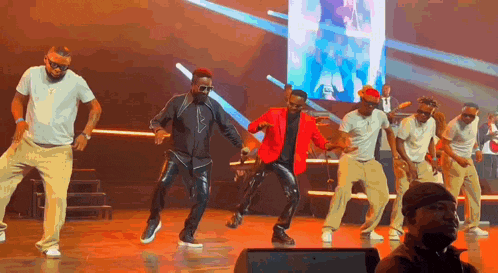 a group of men are dancing on a stage in front of an audience