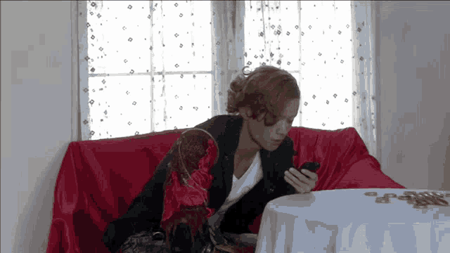 a woman sits on a couch looking at her phone