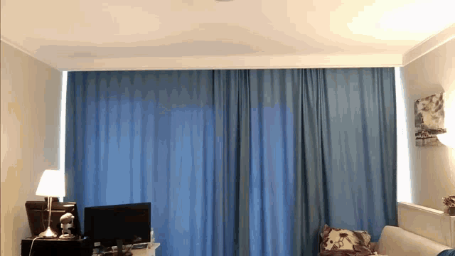 a bedroom with blue curtains and a desk with a computer on it