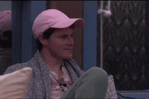 a man wearing a pink hat and a sweater is sitting in front of a window