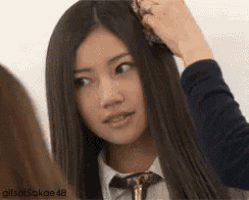 a girl with long black hair and a tie is looking at the camera .