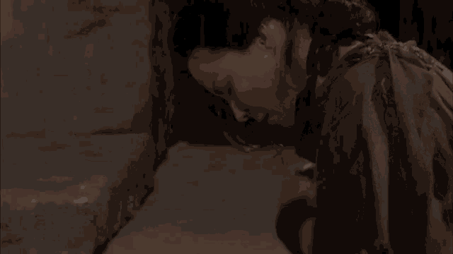 a woman is kneeling down in a dark room looking down .