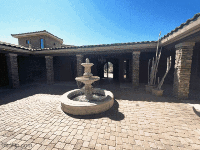 a brick courtyard with a fountain in the middle and a watermark that says imgflip.com on the bottom