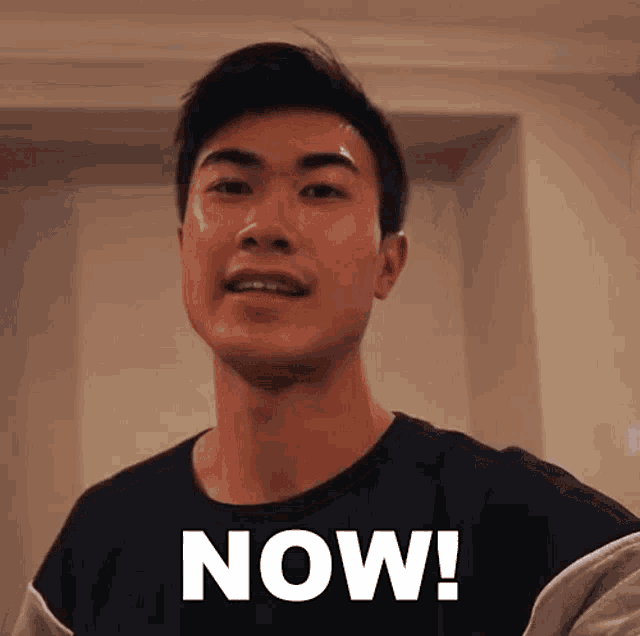 a man in a black shirt with the word now written on it