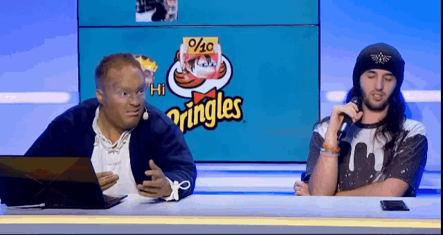 two men sitting in front of a pringles logo