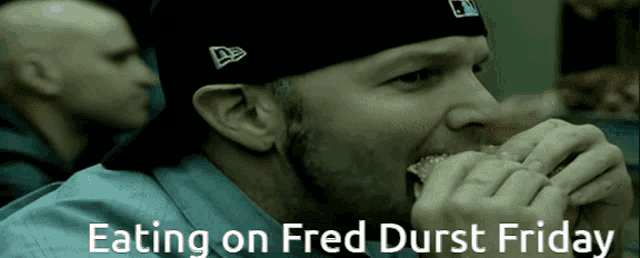 a man is eating a hamburger with the words eating on fred durst friday