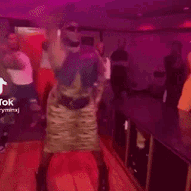 a man in a zebra print dress is dancing in a room with other people .