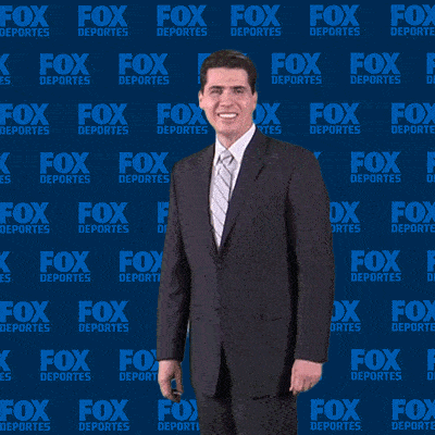 a man in a suit and tie is clapping in front of a fox deportes wall