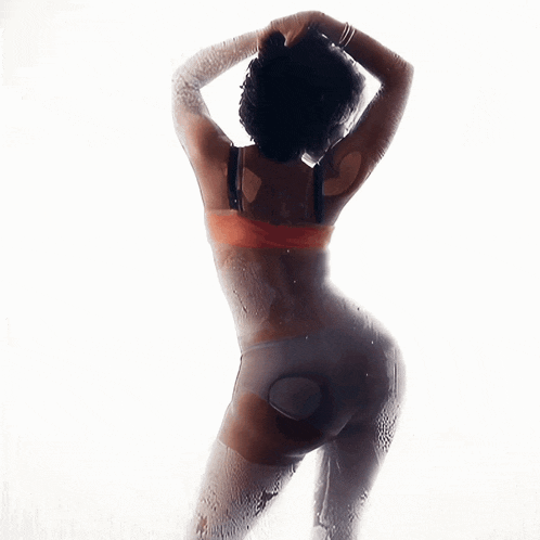 a woman in lingerie stands in front of a window