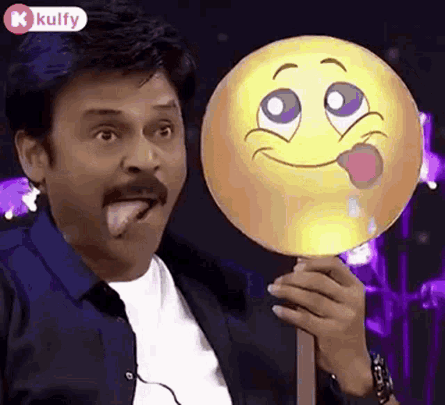 a man with a mustache is sticking out his tongue while holding a smiley face .