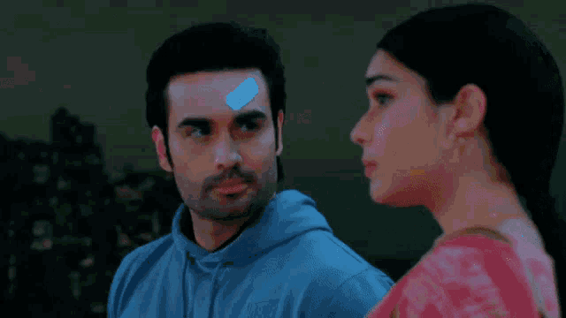 a man and a woman are looking at each other . the woman is wearing a pink saree .
