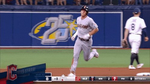 a baseball player wearing a cleveland jersey is running to first base