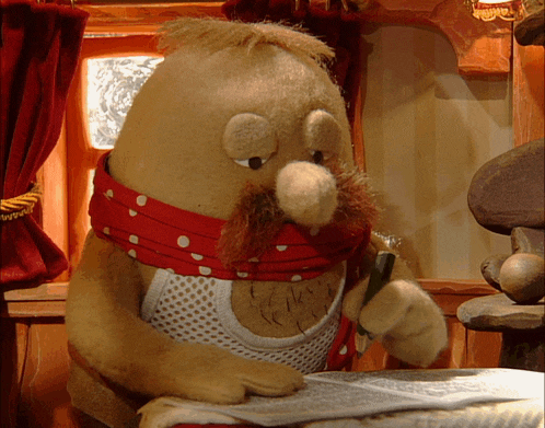 a stuffed animal with a polka dot scarf around its neck is writing on a piece of paper