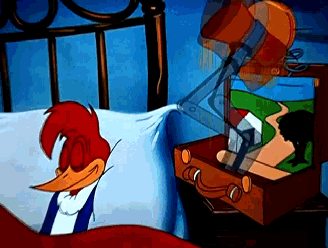 woody woodpecker is laying in bed next to a suitcase with a picture inside of it
