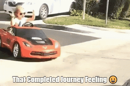 a man is driving a red toy car on a street with the caption that completed journey feeling ..