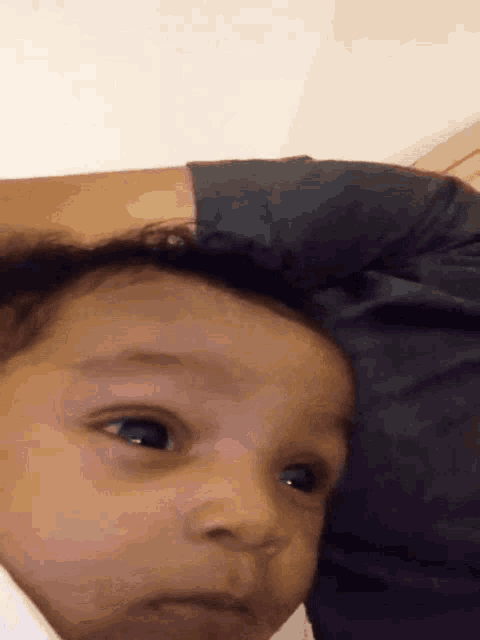 a close up of a baby 's face with a person holding it
