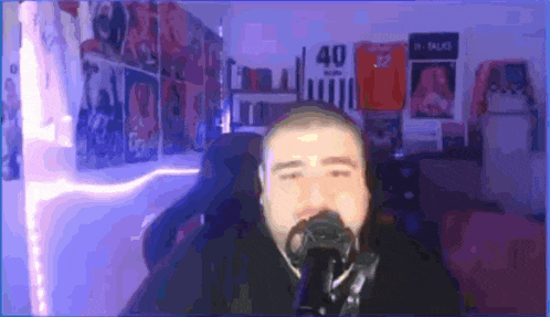 a man with a beard is singing into a microphone in front of a wall with a jersey that says 40