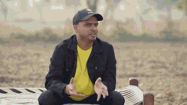 a man wearing a black hat and a yellow shirt has his hands outstretched