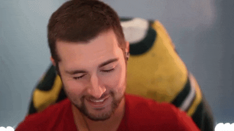 a man in a red shirt is smiling in front of a green bay packers jersey .