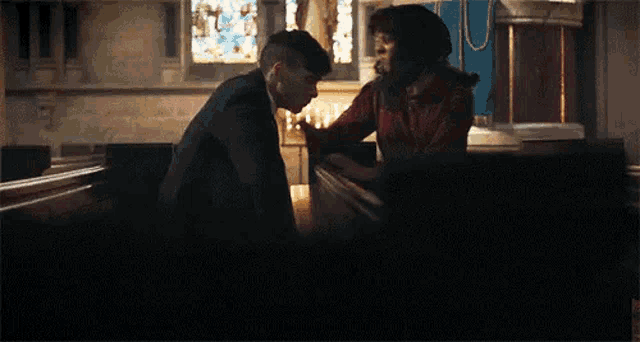 a man and a woman are sitting in a church and kissing .