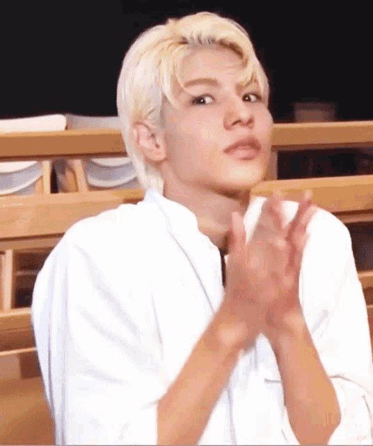 a man with blonde hair is clapping his hands in a classroom