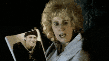 a woman is holding a picture of a man in a black hat