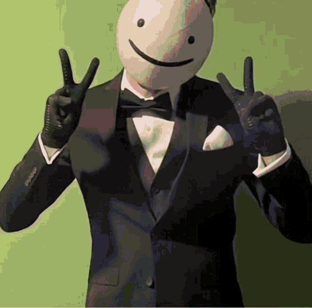 a man in a tuxedo with a smiley face on his face giving the peace sign