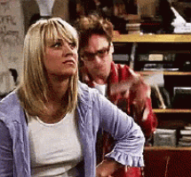 a woman in a blue cardigan is standing next to a man in a red plaid shirt .