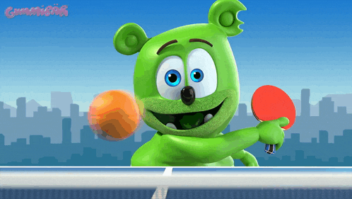 a green gummy bear is holding a ping pong paddle and an orange ball