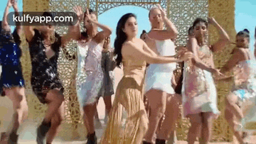 a group of women are dancing together in front of a wall .