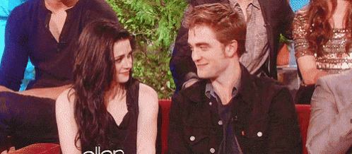 a man and a woman are sitting next to each other on a couch and smiling at each other .