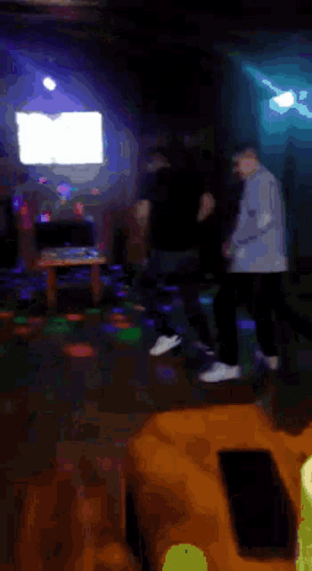 a group of people are dancing in a dark room with lights on the floor