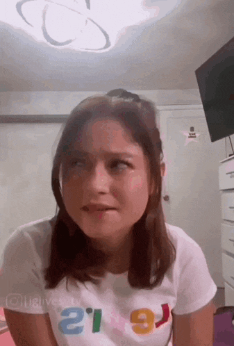 a girl wearing a shirt that says ' e ' on it is making a funny face