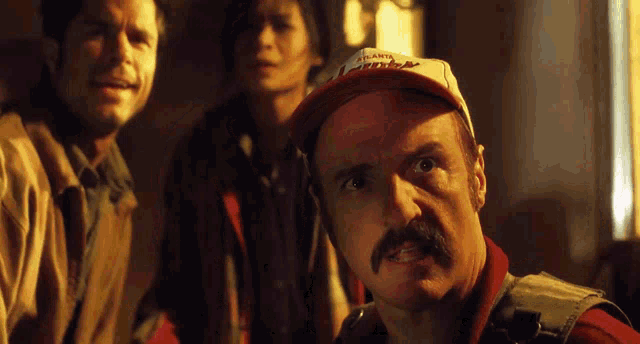 a man with a mustache is wearing an atlanta braves hat