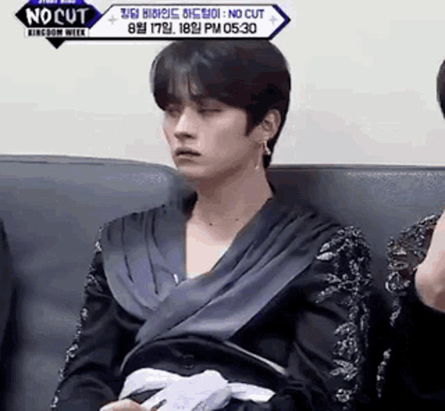 a man is sitting on a couch with his eyes closed and a woman is sitting behind him .
