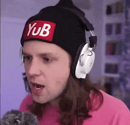 a man wearing a beanie and headphones is making a funny face while talking into a microphone .