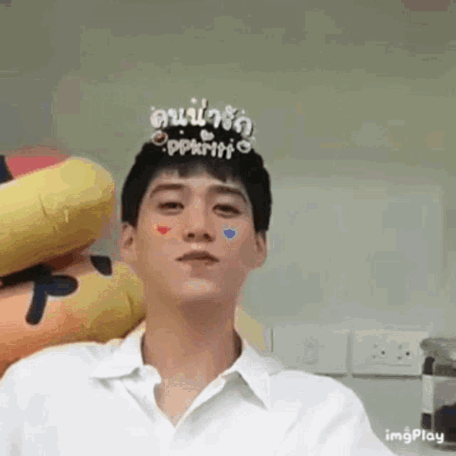 a man wearing a crown on his head is sitting in front of a stuffed animal .