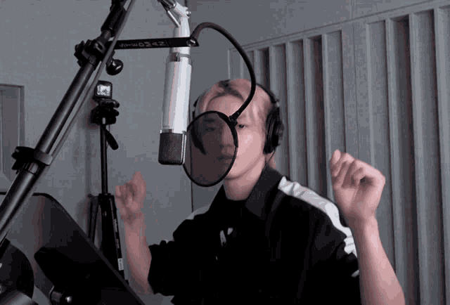 a person wearing headphones stands in front of a microphone with a sticker on it that says ' power daz '