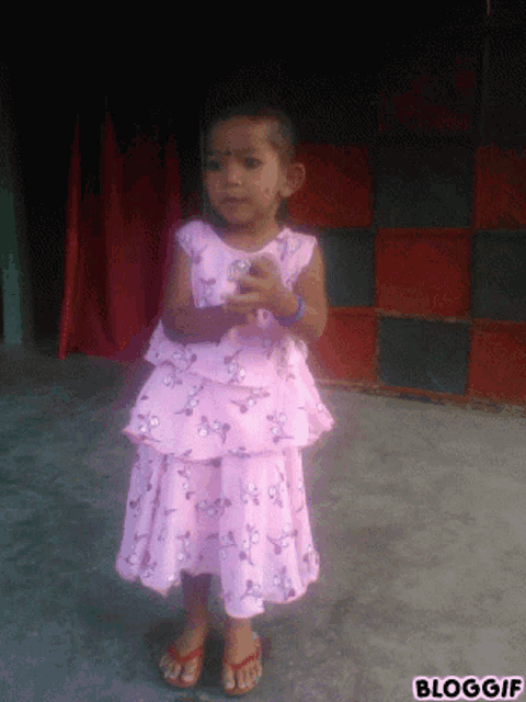 a little girl wearing a pink dress and flip flops
