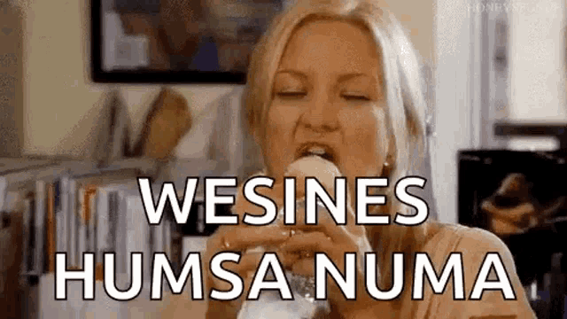 a woman is eating a sandwich with the words wesines humsa numa written on it .