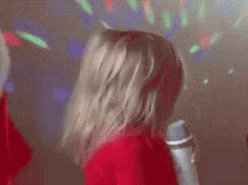 a woman in a red dress is singing into a microphone in a club .