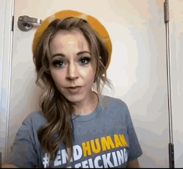 a woman wearing a yellow hat and a t-shirt that says " endhuman felcking "