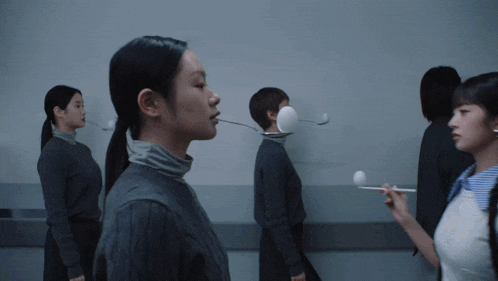 a group of women are standing in a hallway with spoons sticking out of their mouths
