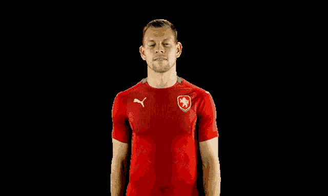 a man wearing a red puma shirt giving a thumbs down sign