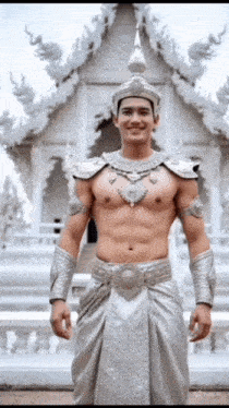 a shirtless man in a silver costume is standing in front of a white building