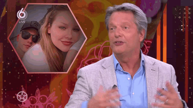 a man in a suit is talking in front of a picture of a woman and a man with the number 6 on the bottom