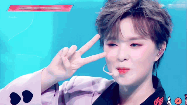 a woman making a peace sign in front of a blue background