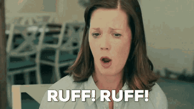 a woman is sitting at a table with her mouth open and the words `` ruff ! ruff ! '' written on the screen .